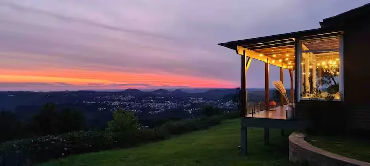 Chalé do Josef ao pôr do sol, vista da fachada com o céu em tons de rosa e laranja