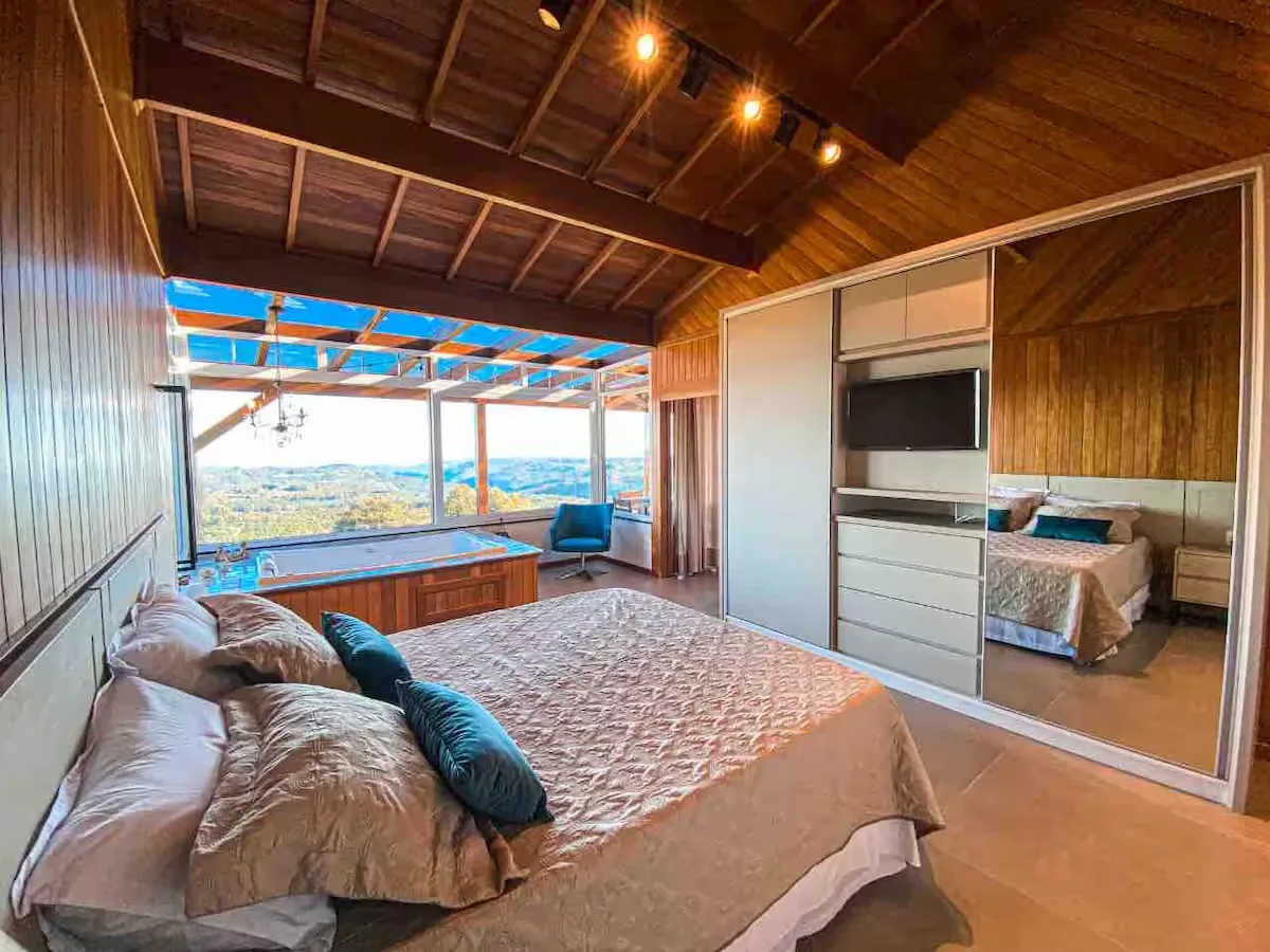 Quarto do Chalé do Josef com cama de casal e jacuzzi ao fundo